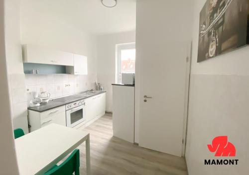 una cocina con armarios blancos, una mesa y una barra en Schöne Monteurwohnung in Bremen-Gröpelingen, en Bremen