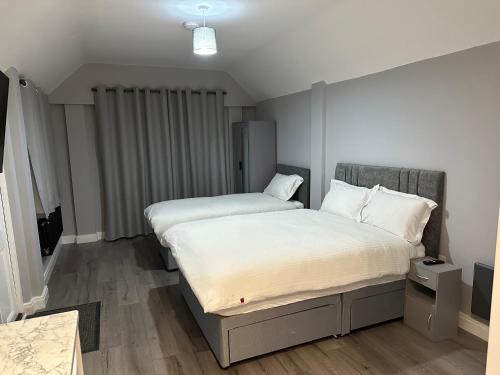 um quarto com 2 camas e lençóis brancos em Ruxley Studios em Orpington