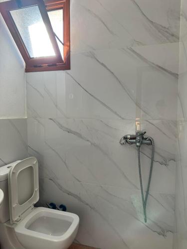 a bathroom with a white toilet and a window at Elite Inn in Vlorë