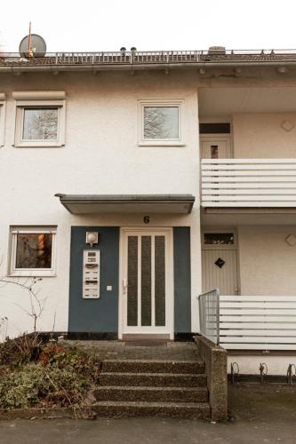 a white house with a blue door and stairs at Ferienwohnung in Kassel
