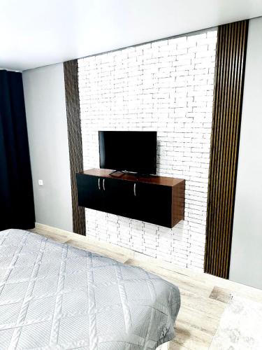 a bedroom with a tv on a white brick wall at Независимости 5а in Sätbaev