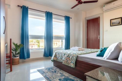 Schlafzimmer mit blauen Vorhängen und einem großen Fenster in der Unterkunft Borail Homes in Silchar