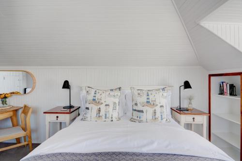 a bedroom with a white bed with two tables and two lamps at Beautiful Abalone in Hermanus