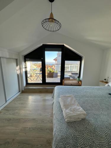 ein Schlafzimmer mit einem Bett und einem großen Fenster in der Unterkunft Duplex Casa da barbeira in Cangas
