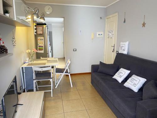 a living room with a black couch and a kitchen at La Terrazza Bella Sicula in Furci Siculo