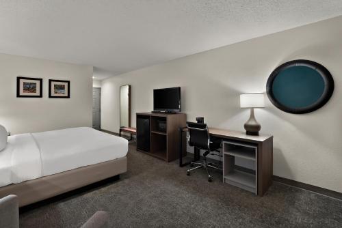 a hotel room with a bed and a desk and a mirror at Comfort Inn & Suites Santee I-95 in Santee