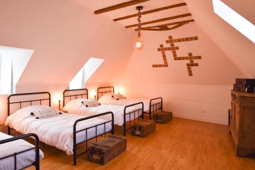 2 łóżka w pokoju na poddaszu z krzyżem na ścianie w obiekcie La Maison de Blanche , Charme et Caractere Aveyron w mieście Luc