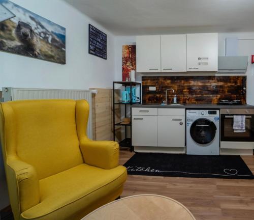 een gele stoel in een woonkamer met een keuken bij Haus Faninger - SUMMERCARD included in Kaprun