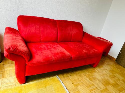 um sofá vermelho sentado no canto de uma sala em Sehr gemütliches und gepflegtes Zimmer 8 Km von Bern-City em Köniz