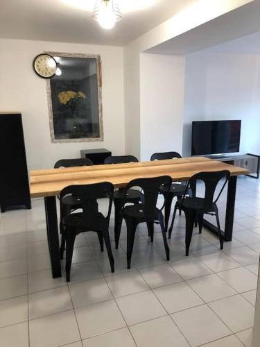 a large wooden table with chairs and a clock on the wall at Chez Sophie et Gege. Maison de ville, deux chambres, de plain-pied in Figeac