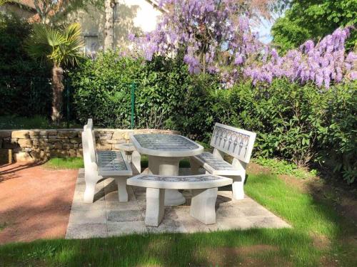 a picnic table and two benches in a garden at Chez Sophie et Gege. Maison de ville, deux chambres, de plain-pied in Figeac