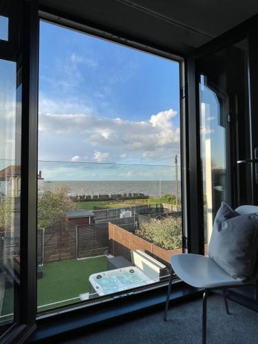 a room with a window with a chair and a view at Broadway Beach Home with Hot tub in Herne Bay