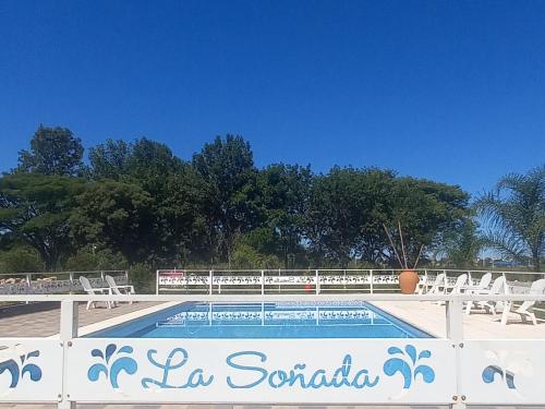 a swimming pool with chairs and a sign on a fence at Cabañas La Soñada in Chajarí
