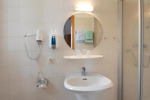a bathroom with a sink and a mirror and a shower at Hotel Münchner Löwenbräu in Cuxhaven