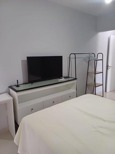 1 dormitorio con TV de pantalla plana en una cómoda en Apartamento aconchegante perto da praia, en Balneário Camboriú