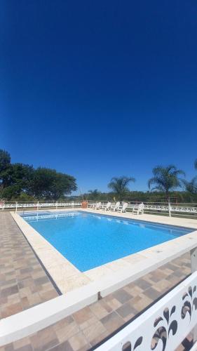 una piscina con sillas y un cielo azul en Cabañas La Soñada en Chajarí