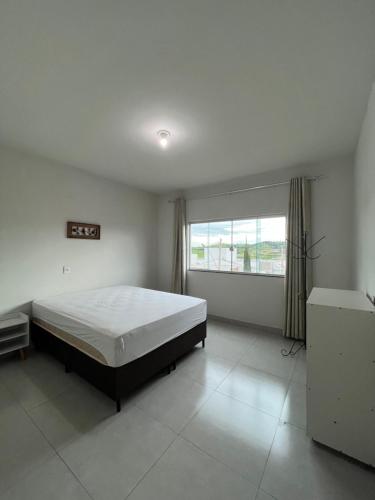 a bedroom with a bed and a large window at Apto Aconchego Capitólio in Capitólio