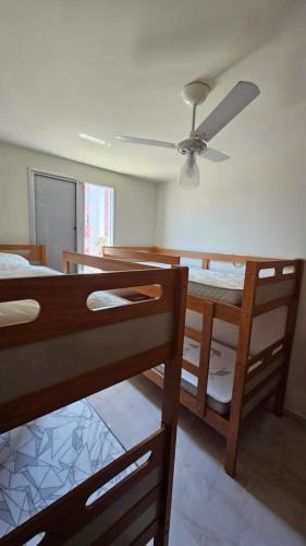 カラグアタトゥーバにあるRecanto na beira da praiaのベッドルーム1室(二段ベッド2台、シーリングファン付)