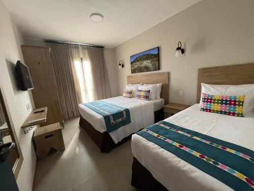 a hotel room with two beds and a television at Quinta Santa Bárbara Eco Resort in Pirenópolis
