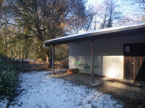 a snow covered yard next to a garage at Chambre triple du grand sapin 