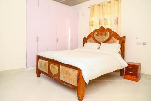 a bedroom with a large bed with a wooden headboard at Baali Diani Apartments in Ukunda