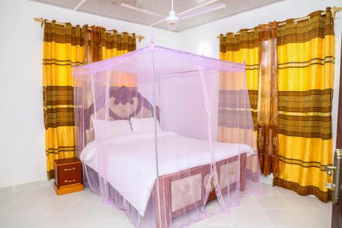 a bedroom with a canopy bed with yellow curtains at Baali Diani Apartments in Ukunda