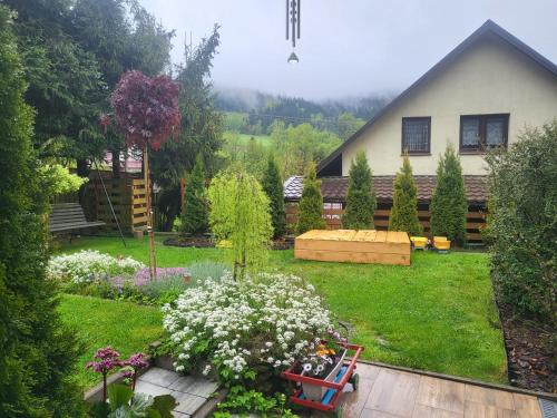 een huis met een tuin met bloemen in de tuin bij Cichy Zakątek in Uście Gorlickie