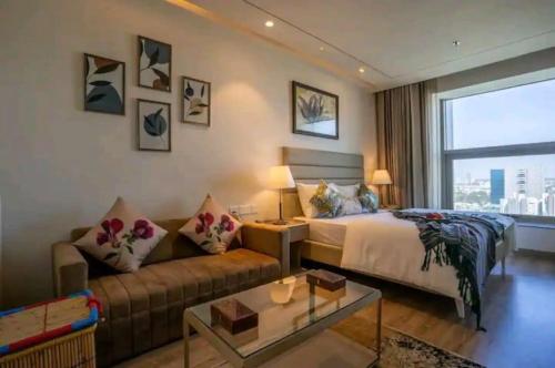 um quarto de hotel com uma cama e um sofá em Luxury Apartment In Gurgaon em Gurgaon