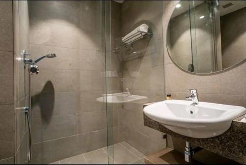 uma casa de banho com um lavatório e uma cabina de duche em vidro. em Luxury Apartment In Gurgaon em Gurgaon