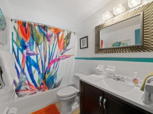 W łazience znajduje się umywalka, toaleta i lustro. w obiekcie Uptown Cottage - Walk to the Beach and Restaurants w mieście Cocoa Beach