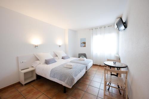 een slaapkamer met een bed en een kleine tafel bij Hostal el Ranxo in Cadaqués