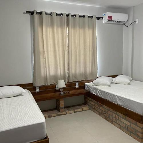 a room with two beds and a window at ponta do papagaio in Palhoça