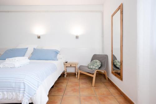 a bedroom with a bed and a mirror and a chair at Hostal el Ranxo in Cadaqués
