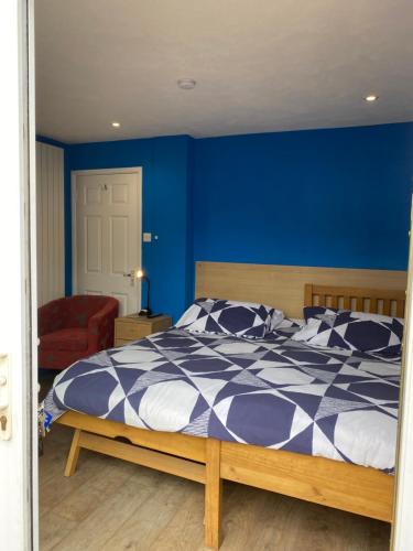 um quarto com uma cama com uma parede azul em Heather's Lodge em Cheshunt