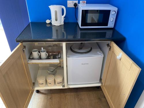 a kitchen with a counter top with a microwave at Heather's Lodge in Cheshunt