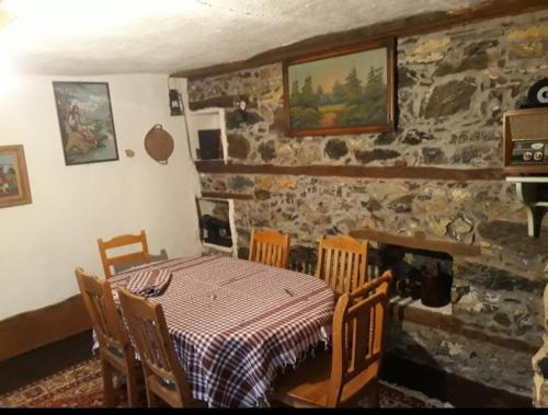 jadalnia ze stołem i krzesłami oraz kamienną ścianą w obiekcie Etno kuca-Vila w mieście Štrpce