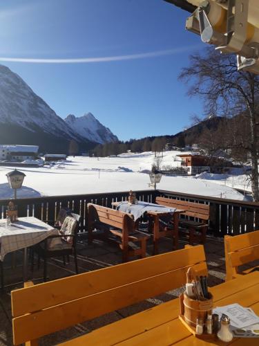 ein Restaurant mit Holztischen und schneebedeckten Bergen in der Unterkunft Haus am Lärchenhang, Fewo5 in Leutasch