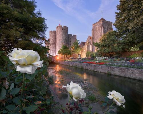 a river with white roses in front of a castle at The Castle City Centre Apartment in Canterbury