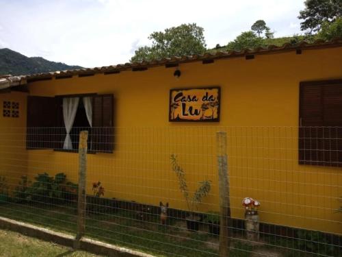 a yellow house with a sign that reads lease dog lick at Casa da Lu in Macaé