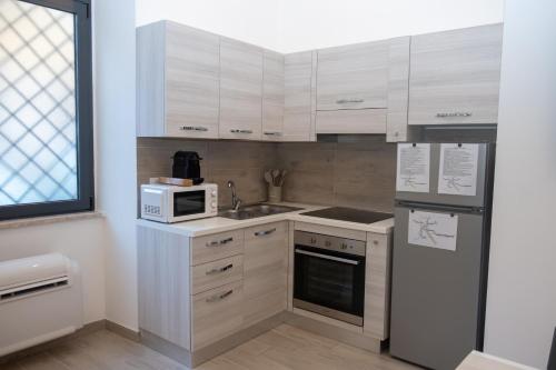 a kitchen with white cabinets and a sink and a microwave at DOMVS Ginori Testaccio in Rome