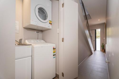 a white laundry room with a washer and dryer at Sovereign Pier On The Waterways in Whitianga