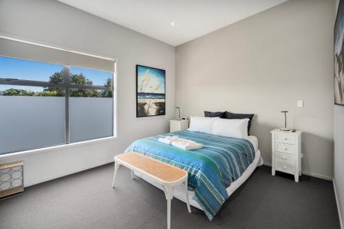 a bedroom with a bed and a table and a window at Sovereign Pier On The Waterways in Whitianga