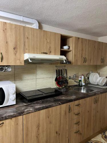a kitchen with wooden cabinets and a sink and a microwave at Privat FoRest in Liptovský Mikuláš