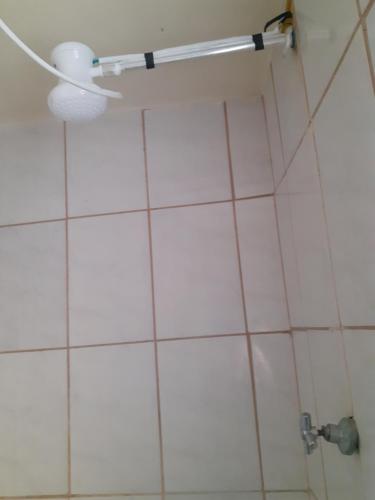 y baño con ducha y pared de azulejos blancos. en Espaço igor, en Aparecida