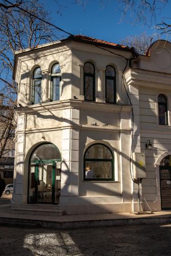 a white building with arched windows on a street at Kula Centar in Trebinje