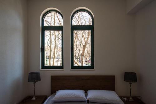 two windows in a room with a bed and two lamps at Kula Centar in Trebinje