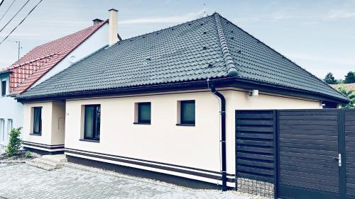 a white house with a black roof and a garage at Dům Pálava in Perná