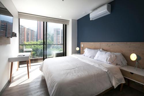 une chambre avec un grand lit et une grande fenêtre dans l'établissement CLASS DE SUITES DE LUJO EL POBLADO. EXCELENTE UBICACIÓN, à Medellín