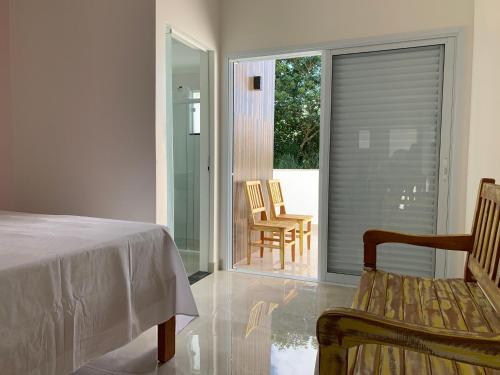 a bedroom with a bed and a balcony with chairs at São Francisco Flats in Guapé