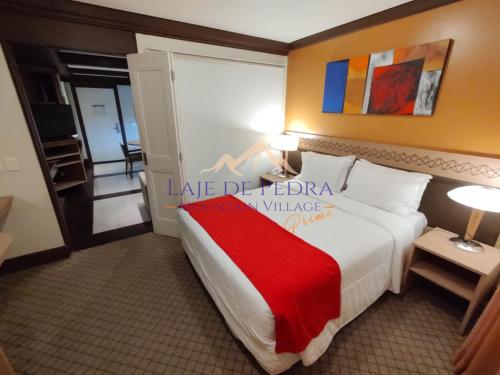 a hotel room with a large bed with a red blanket at Laje de Pedra Mountain VillagePrime in Canela